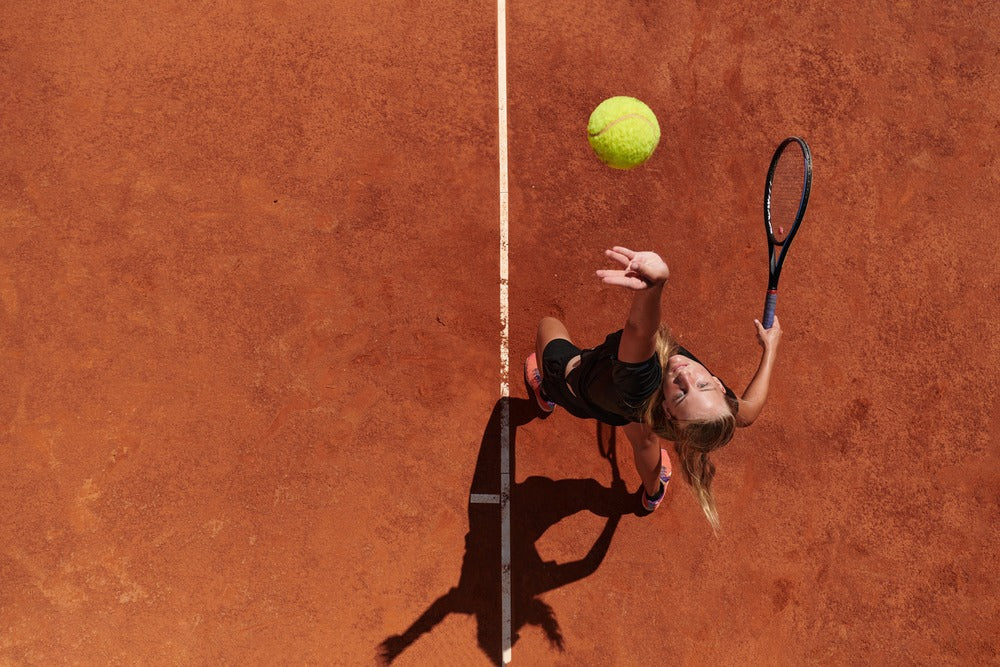 woman playing tennis on clay court